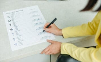 Jak planować posiłki na cały tydzień kiedy nienawidzę stać przy garach i brakuje mi czasu Kobieta planująca tygodniowe posiłki na liście w domu