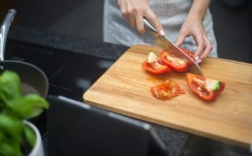Kobieta kroi czerwoną paprykę w nowoczesnej kuchni